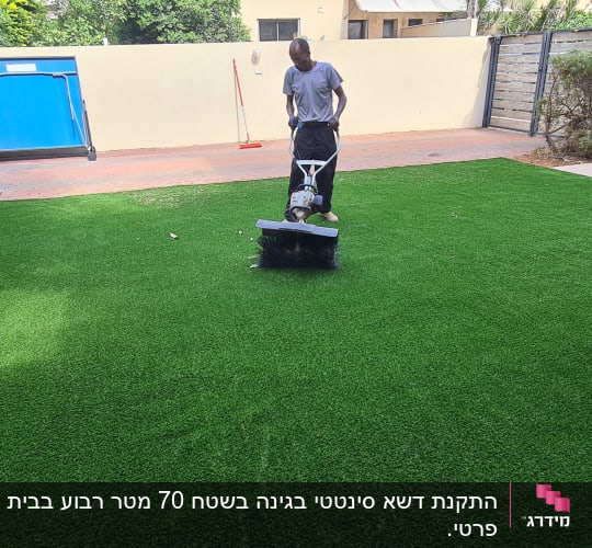 אדם משתמש במכונה על דשא סינתטי בחצר